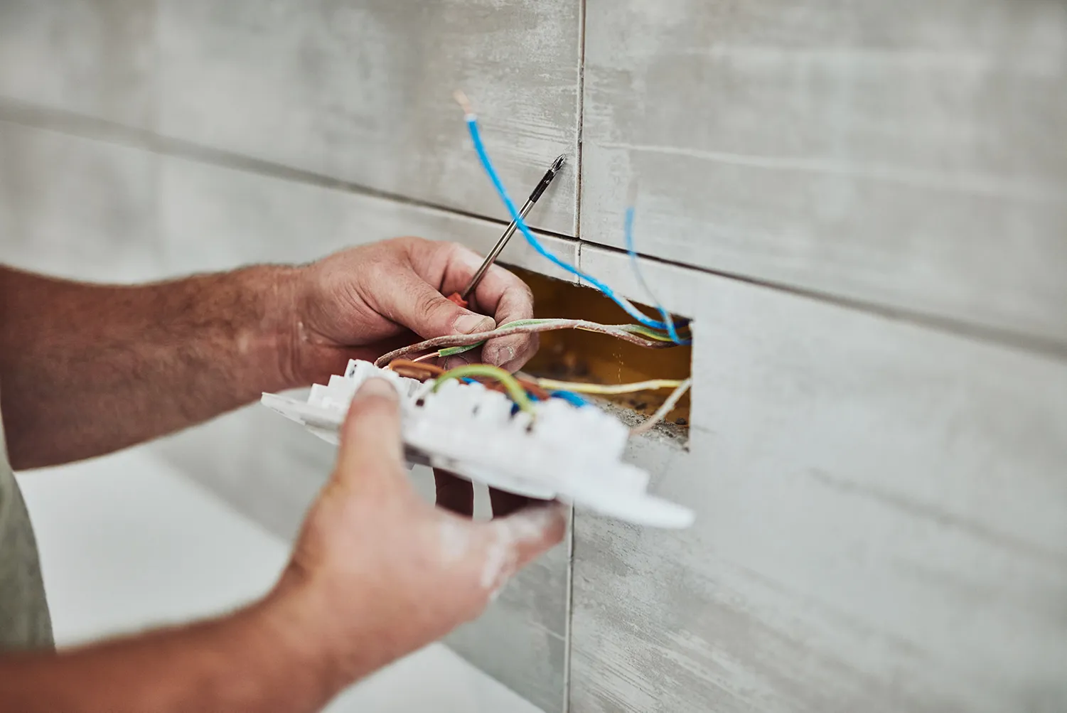 Elektriker repariert/fixiert Kabel in der Wand.
